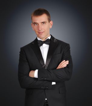 young businessman in tuxedo on black background