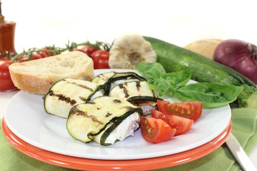 stuffed courgette rolls and tomatoes on a white plate