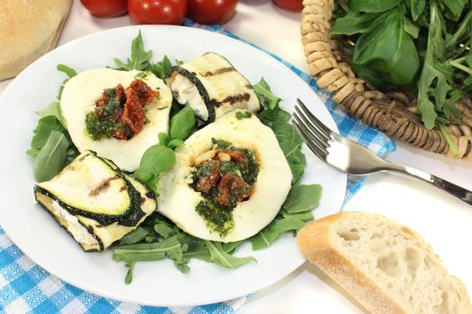 Zucchini rolls and stuffed mozzarella with arugula on a light background