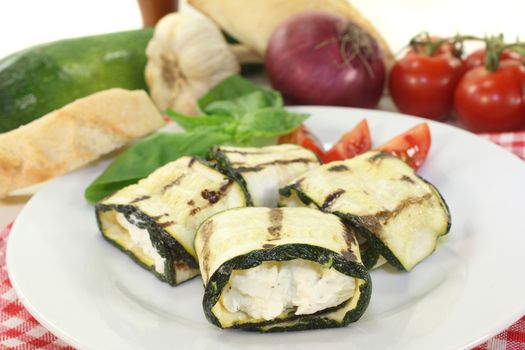 stuffed courgette rolls and tomatoes on a white plate