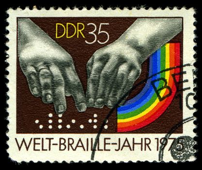 DDR- CIRCA 1975: A stamp printed in DDR, shows  hands reading a font of Braille , circa 1975