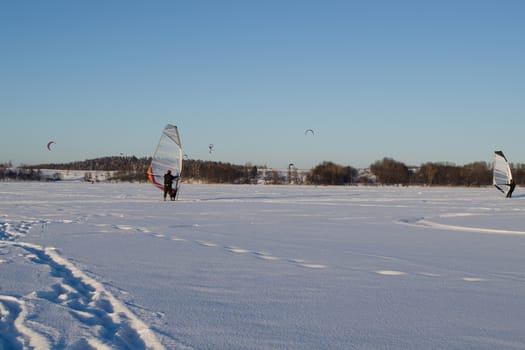 Lot of people ice sailing surfing and kiteboarding on frozen Galves lake in Trakai amazing cold winter day.