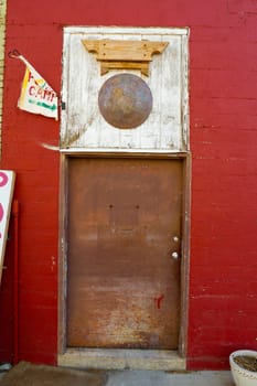 An old rusty door on a red brick building that leads to somewhere is very interesting in this vertical color photograph image.