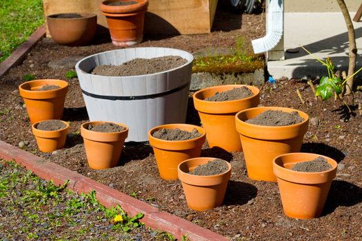 A small garden is ready to be planted consisting of terracotta pots and potting soil right now waiting for the plants.