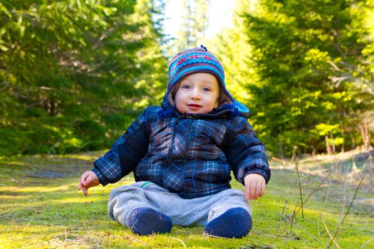 A young boy wears a jacket and warm hat while hiking in the cold near snow in the winter and having fun exploring.