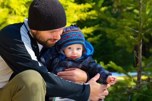 A father and son stop for a moment to share some time playing in the snow on a family hiking adventure.