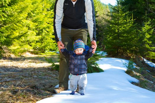 A father and son stop for a moment to share some time playing in the snow on a family hiking adventure.