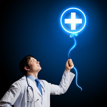 Young male doctor holding balloon with medical sign