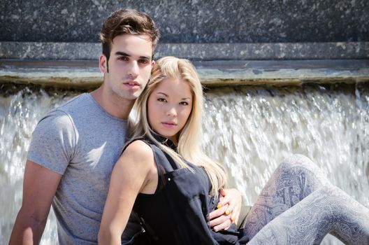 Boyfriend and girlfriend sitting in front of big fountain