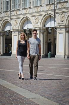 Outdoor shot of boyfriend and girlfriend walking in elegant, european city in the sun