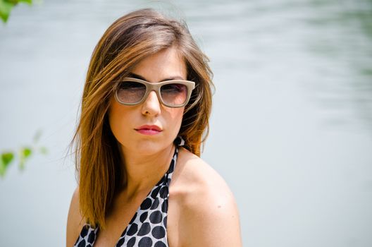 Headshot of pretty brunette girl outdoors in nature looking in camera