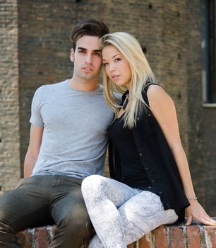 Attractive couple sitting and leaning towards each other looking in camera
