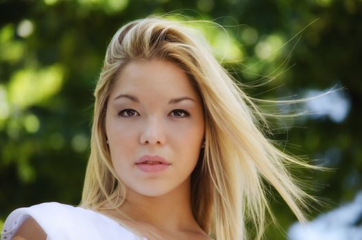 Headshot of pretty blonde girl outdoors in nature looking in camera