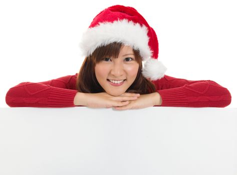 Christmas santa woman smiling cute is showing blank empty billboard sign. Asian Chinese / Japanese  young female model in red Santa hat. Isolated on white background. 