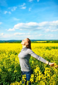 Girl with outstretched arms at colza field