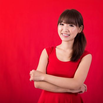 Portrait of cute Asian woman smiling wearing red dress isolated on red background. Asian female model.