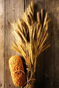 Rye spikelets and bread on wooden background