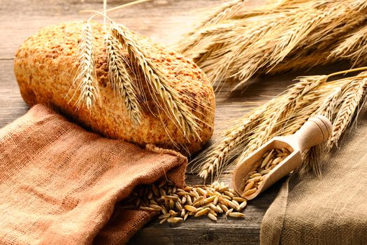 Rye spikelets and bread on wooden background