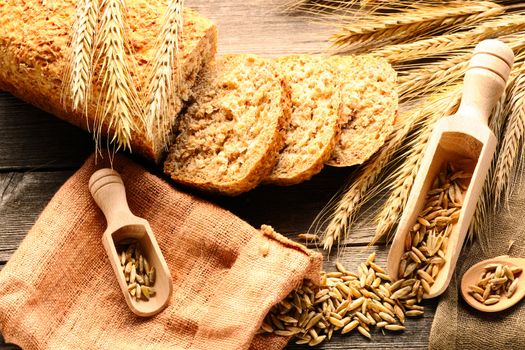 Rye spikelets and sliced bread on wooden background