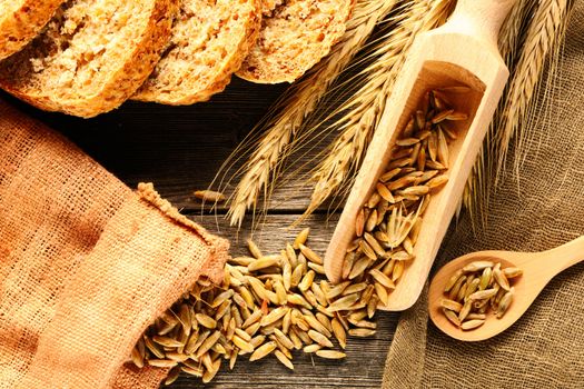 Rye spikelets and sliced bread on wooden background