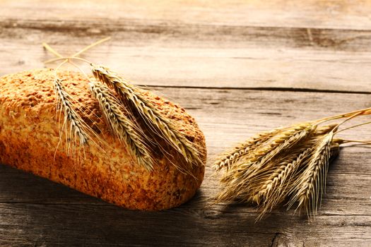 Rye spikelets and bread on wooden background