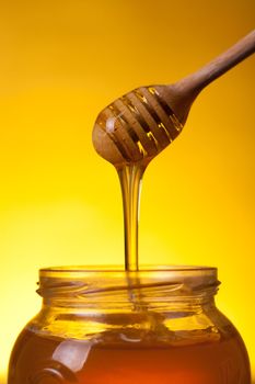 Flowing honey over yellow background 