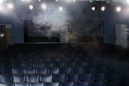 Empty seats of a small old theatre as seen from the stage. Some smoke and lighting effects.