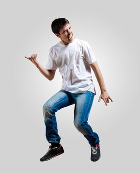 Modern slim hip-hop style man jumping dancing on a grey background