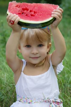 Pretty little girl holding slice of watermelon outdoors
