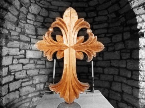 Wooden cross in front of a wall of stones