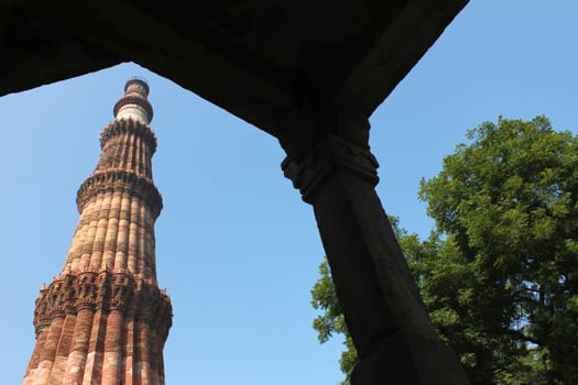 looking through gate qutub minar in blue sky