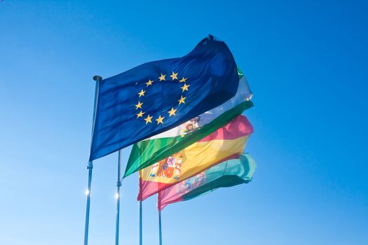 4 flags: the European Union, Andalucia, Spain, Granada, at the fortress of the Alhambra. Spain