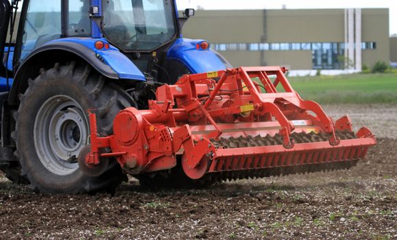 Rear closeup view of a articulated tractor with multiple plows that is plowing the earth