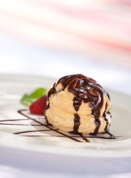 Chocolate profiterole stuffed with ice cream served on a plate