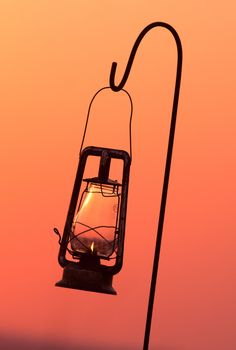 Huricane lamp hanging on a sheppard's crook at sunset