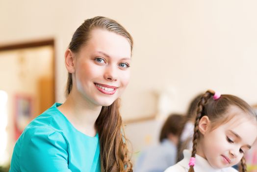 Teacher draws to a girl at a drawing lesson