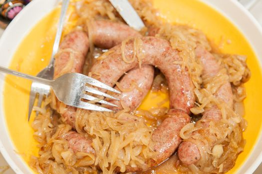 Hot pieces of cooked Polish kielbasa with camelized onions.