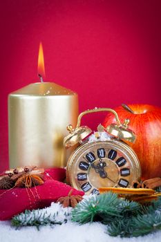 Christmas decorations - clock for the new year, candle, pine branch on red background