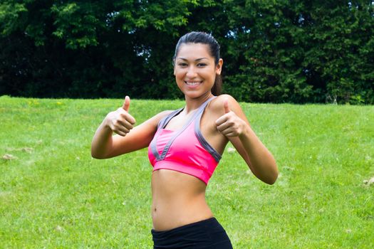 Thumbs up for a fit young woman in the park