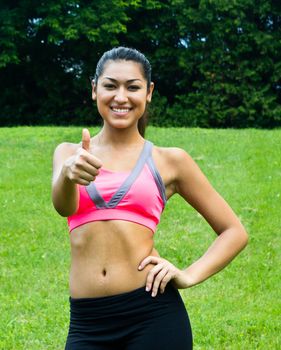 Thumbs up for a fit young woman in the park