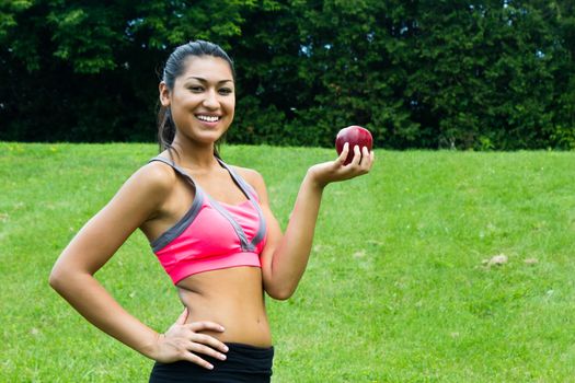 Fit young woman with an apple in the park