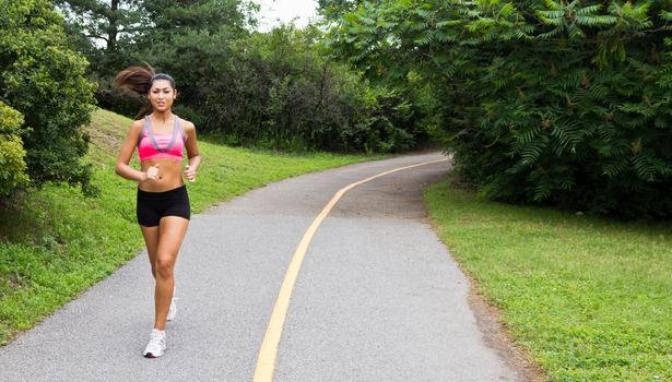 Smiling young woman running for fitness