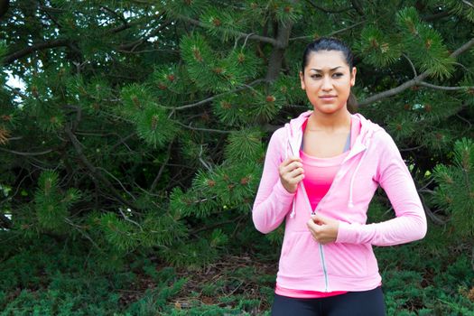 Young woman removing her jacket before a workout