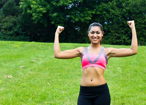 Young fit woman flexes her muscles