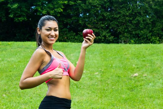 Fit young woman with an apple in the park