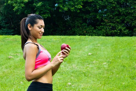 Fit young woman with an apple in the park