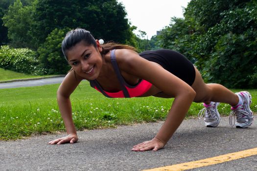 Fit young woman doing push-ups outdoors