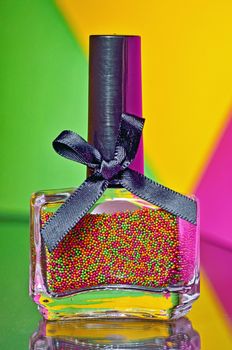 Bottle with colorful nail polish on colorful background