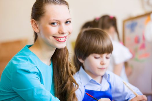 Young teacher and children painting and playing