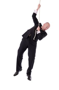 Businessman hanging onto a rope fearing from below isolated on white